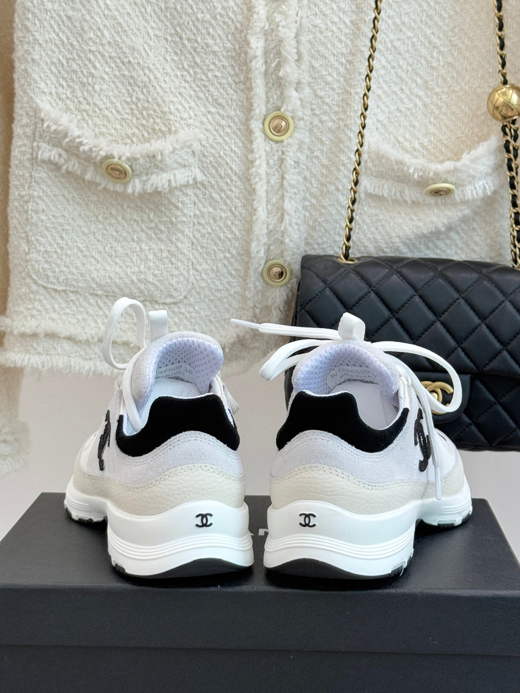 Chanel white sneakers from back view with black heel accents and white laces