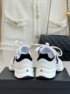Chanel white sneakers from back view with black heel accents and white laces
