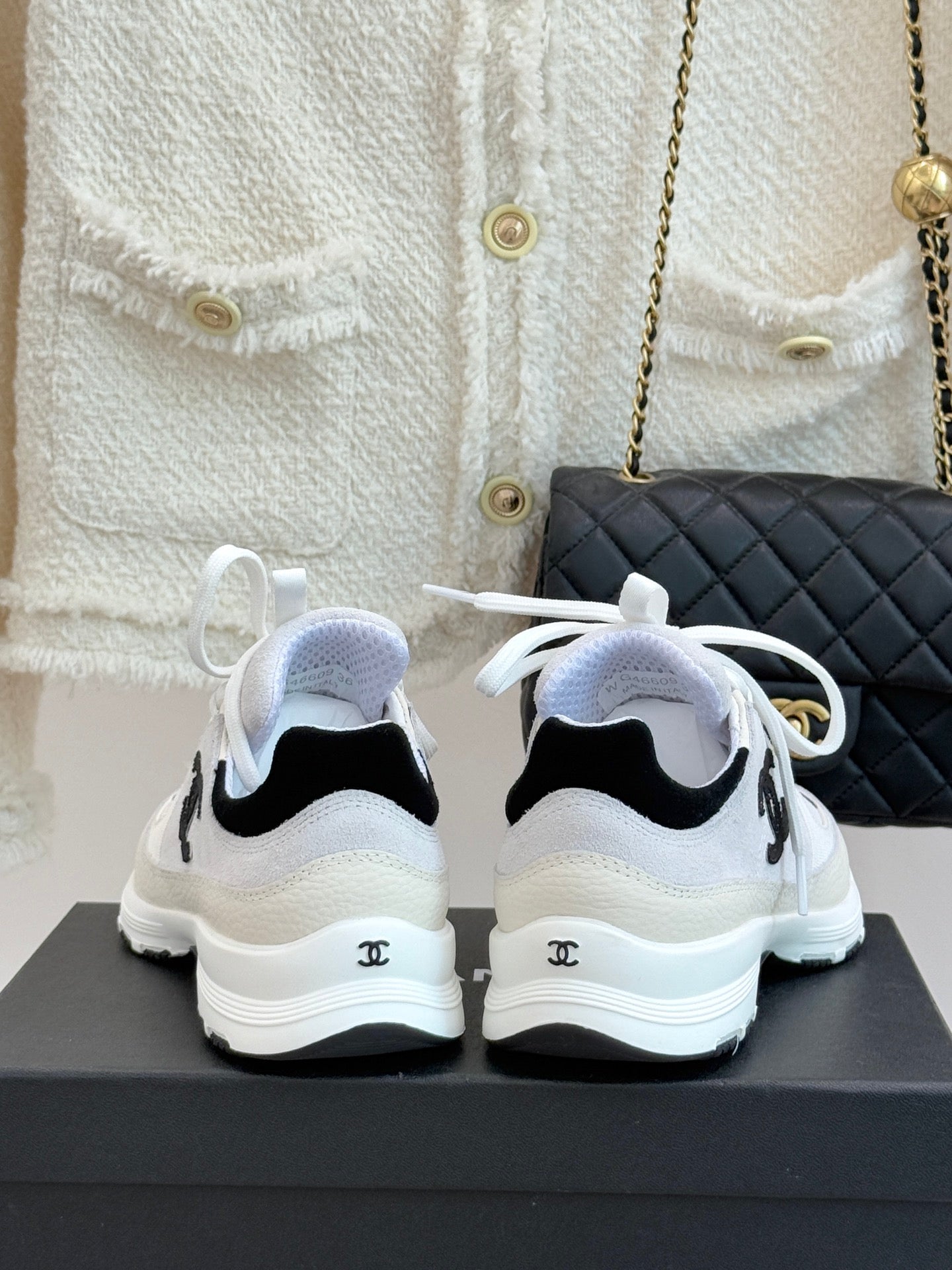 Chanel white sneakers from back view with black heel accents and white laces