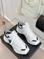 Pair of Chanel white sneakers with black accents and white laces on display box