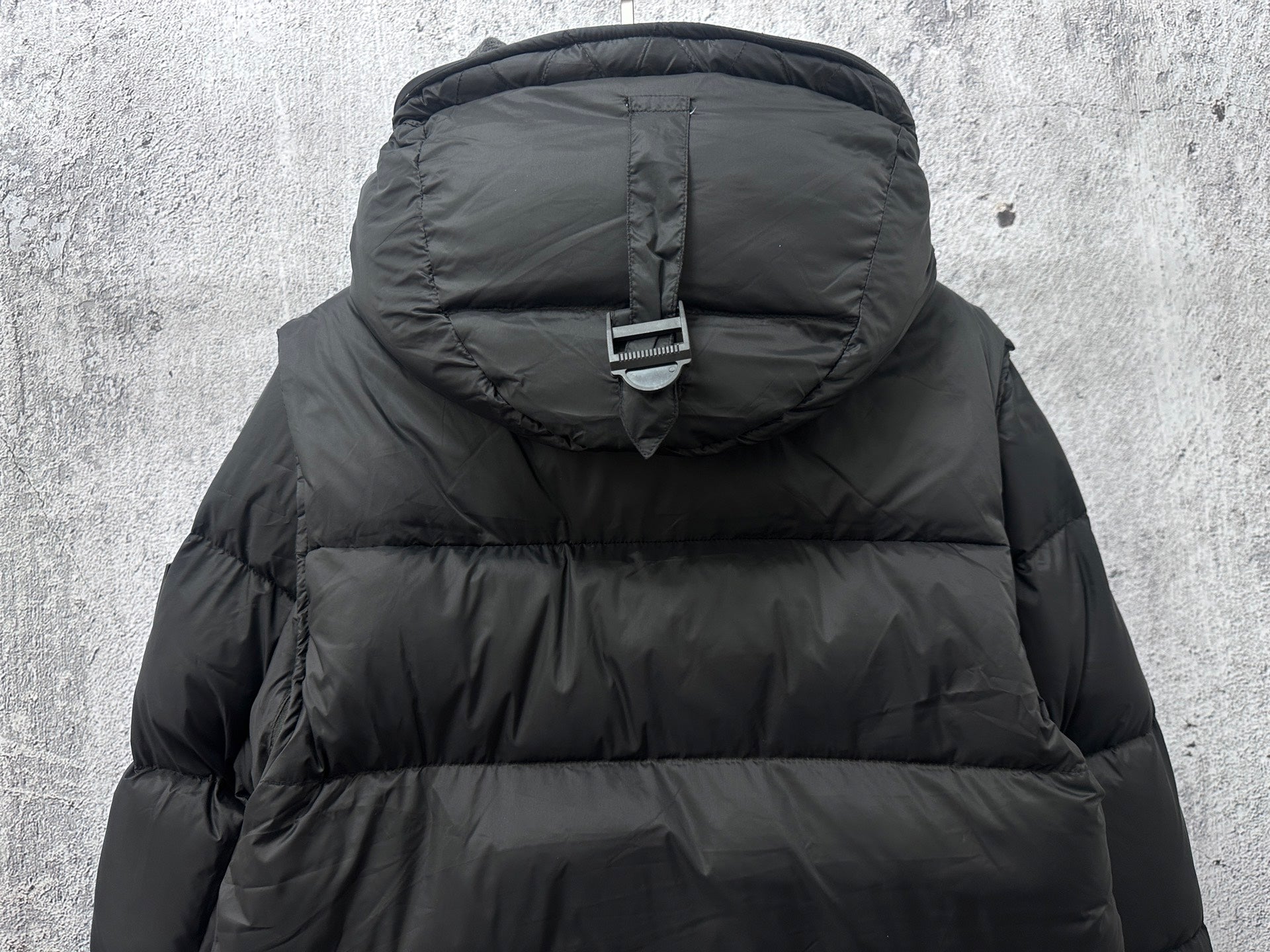 Long quilted puffer jacket with hood and adjustable strap detail, dark color