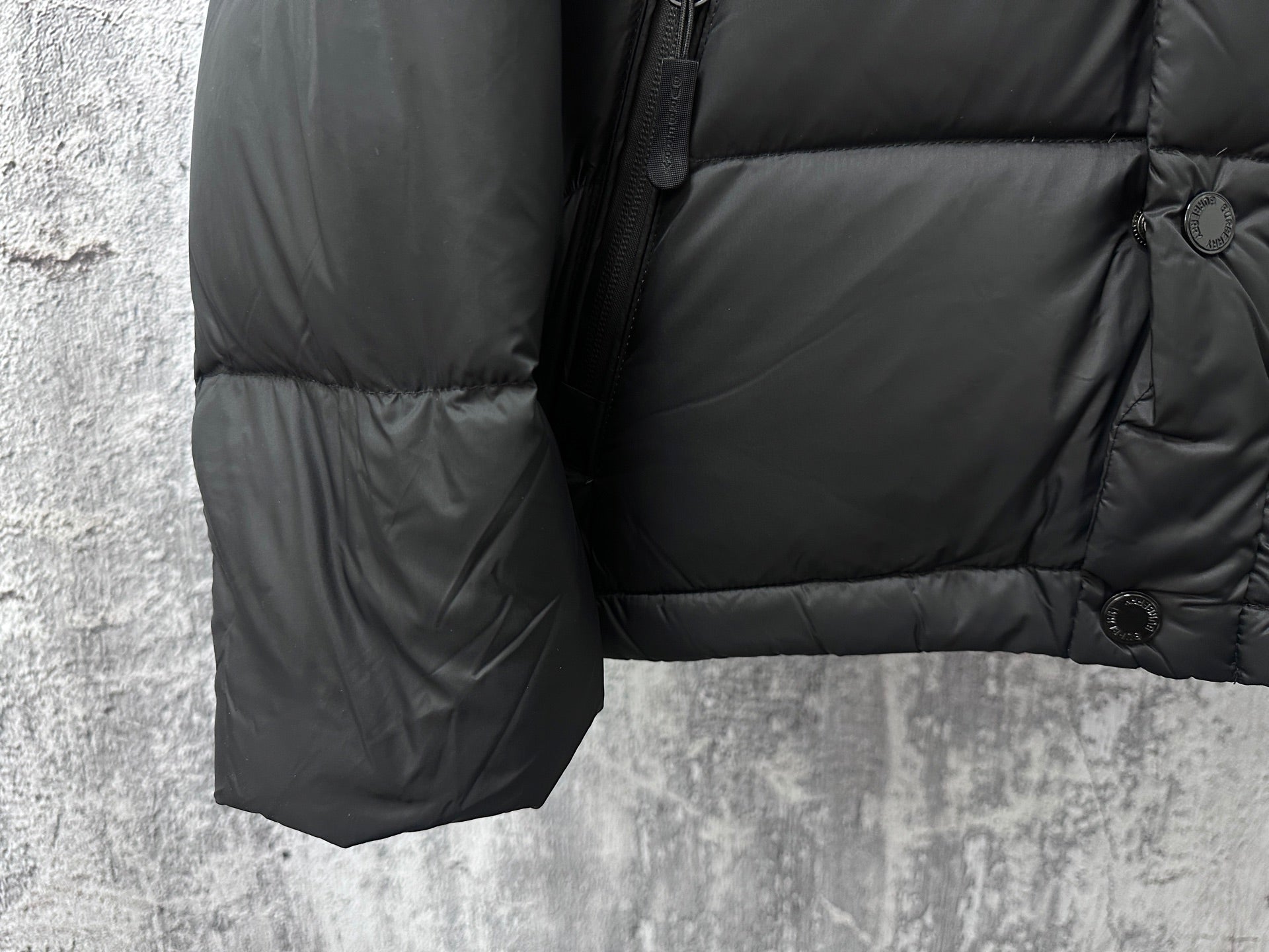 Long puffer jacket sleeve and hem with quilting and button cuff detail