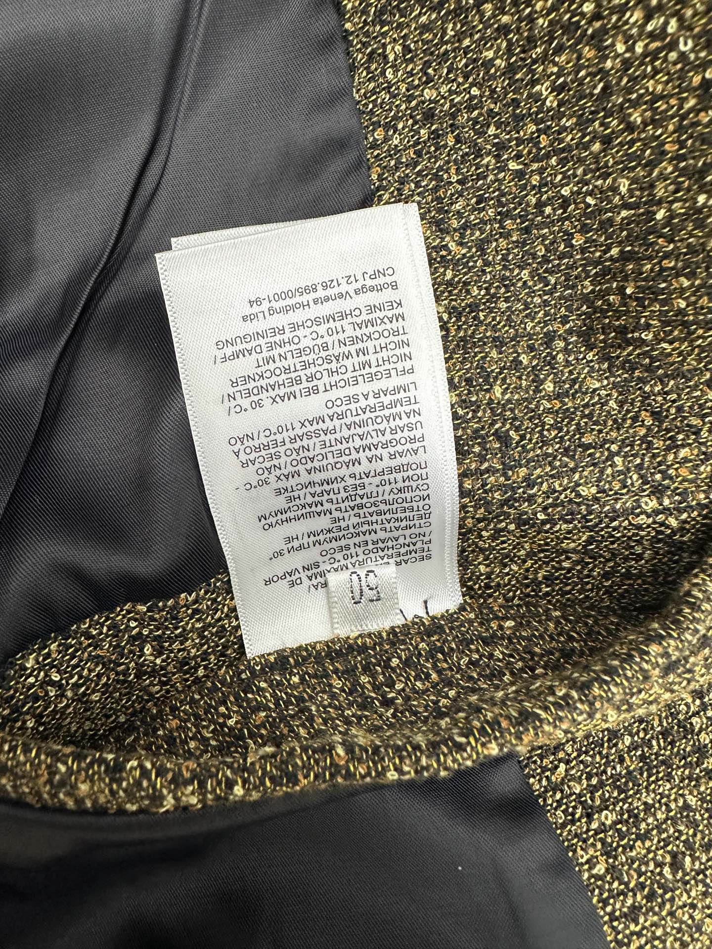Dark jacket with gold sequin cuff trim and care label