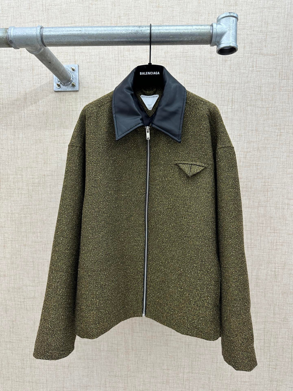 Olive textured jacket with dark blue pointed collar and front zipper closure
