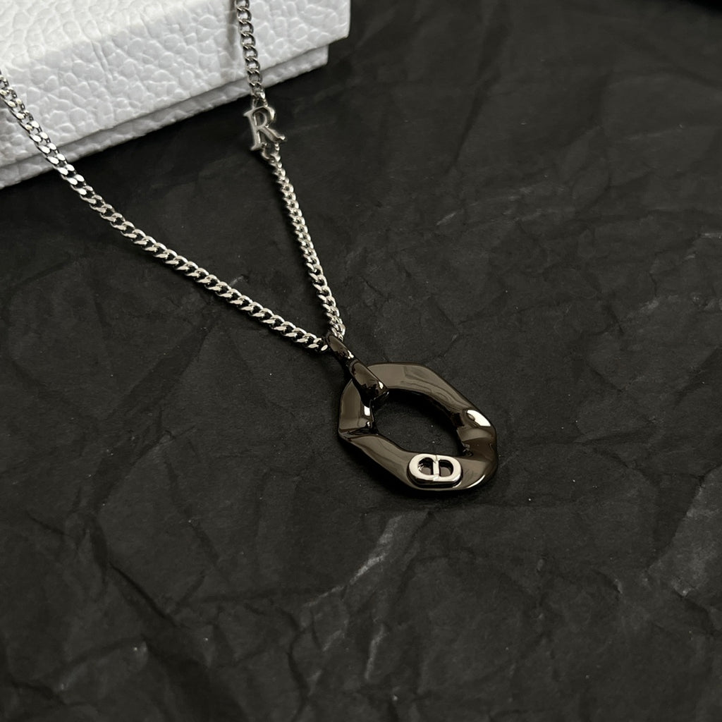 Dior charm necklace close-up with dark oval pendant on silver-tone chain