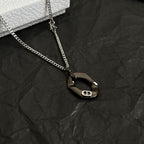 Dior charm necklace close-up with dark oval pendant on silver-tone chain