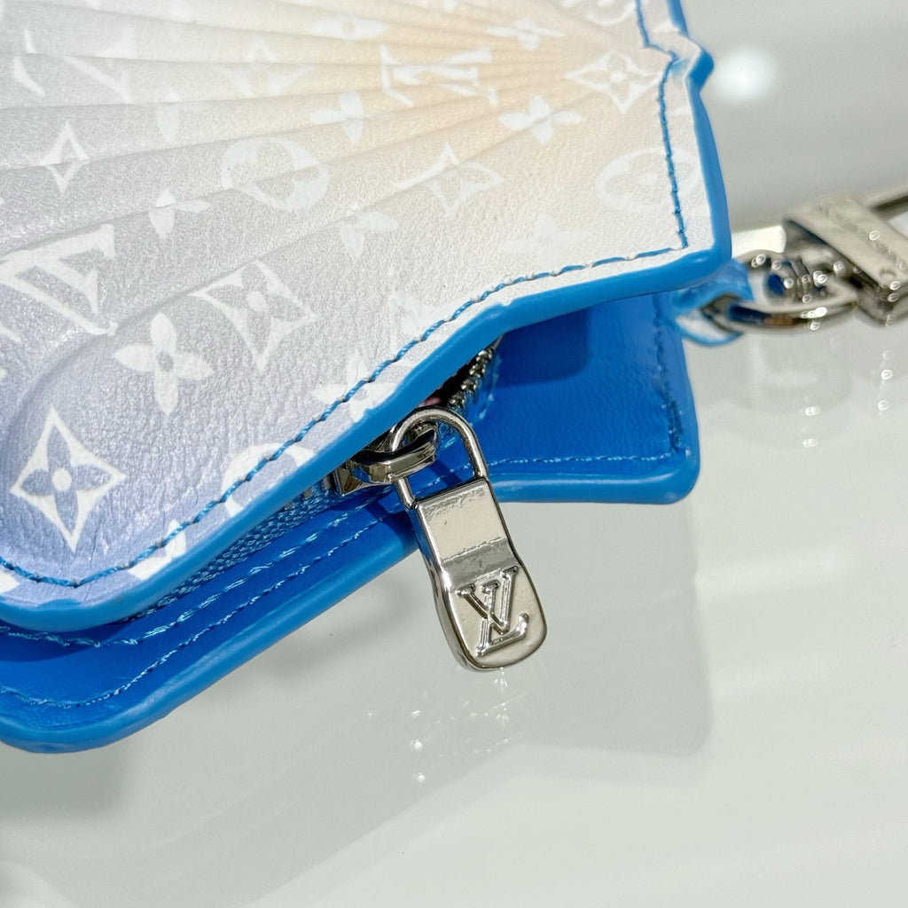 Small monogram pouch bag corner with silver padlock-style clasp and blue strap