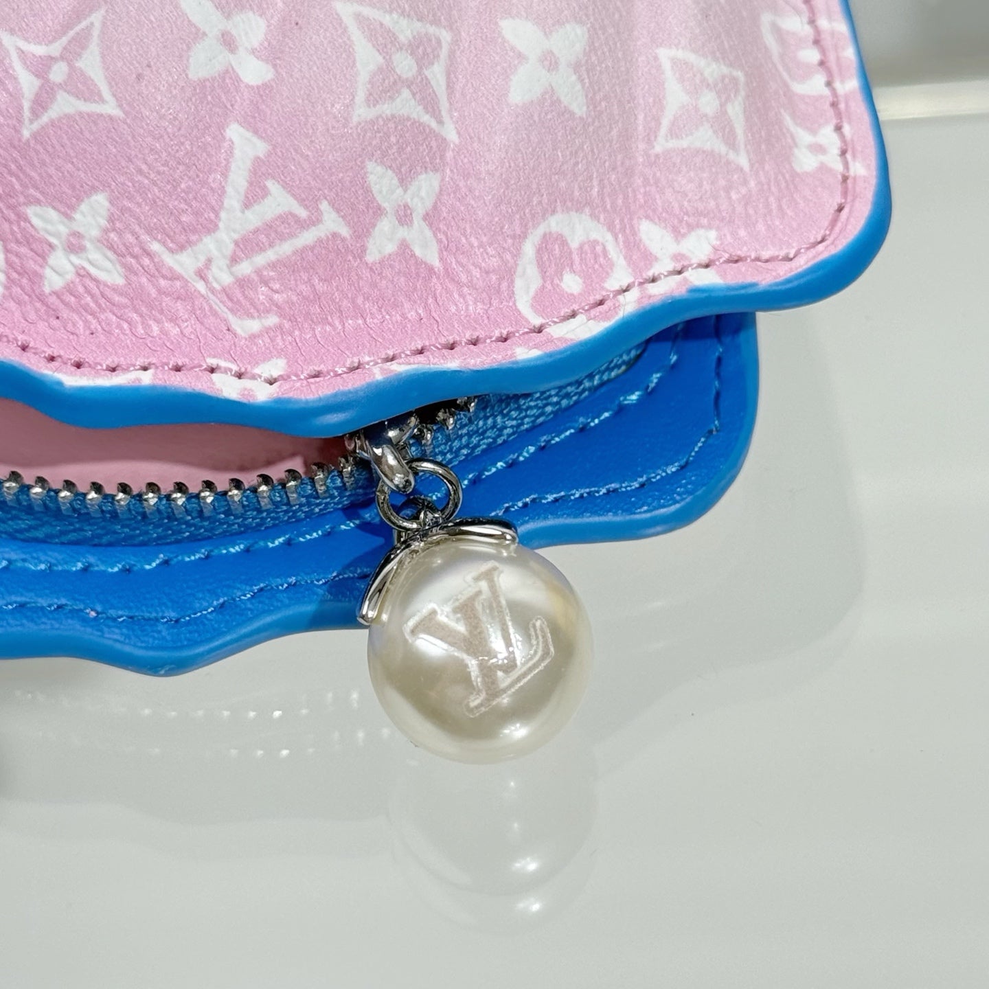 Louis Vuitton shell bag close-up, pink monogram flap, blue border, silver bead charm
