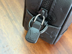 Louis Vuitton monogram bag with metal clasp and strap hardware on dark leather.