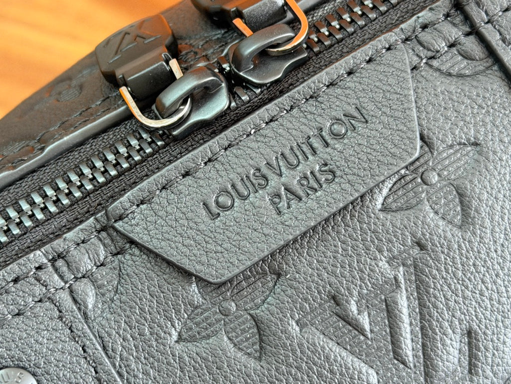 Louis Vuitton bag zipper pull and embossed logo patch on grained dark leather.