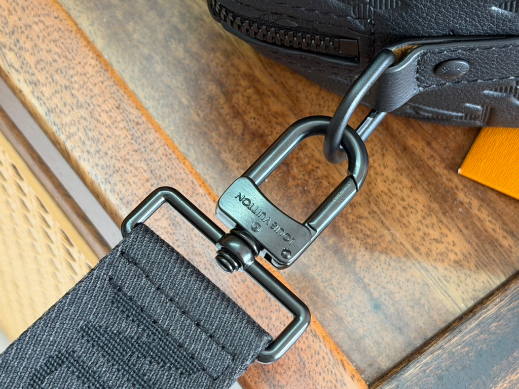 Louis Vuitton bag strap with metal D-ring hardware and embossed logo on strap keeper.