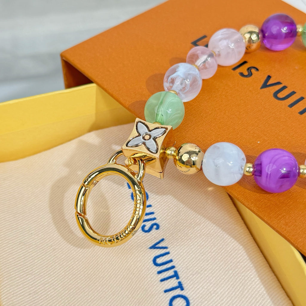 Beaded charm bracelet with gold cat pendant, round beads, and gold key ring
