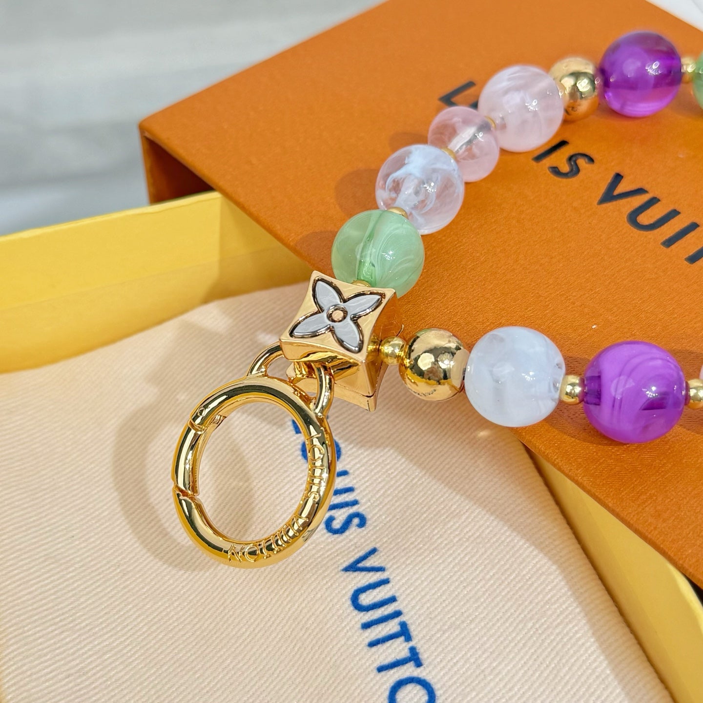 Beaded charm bracelet with gold cat pendant, round beads, and gold key ring