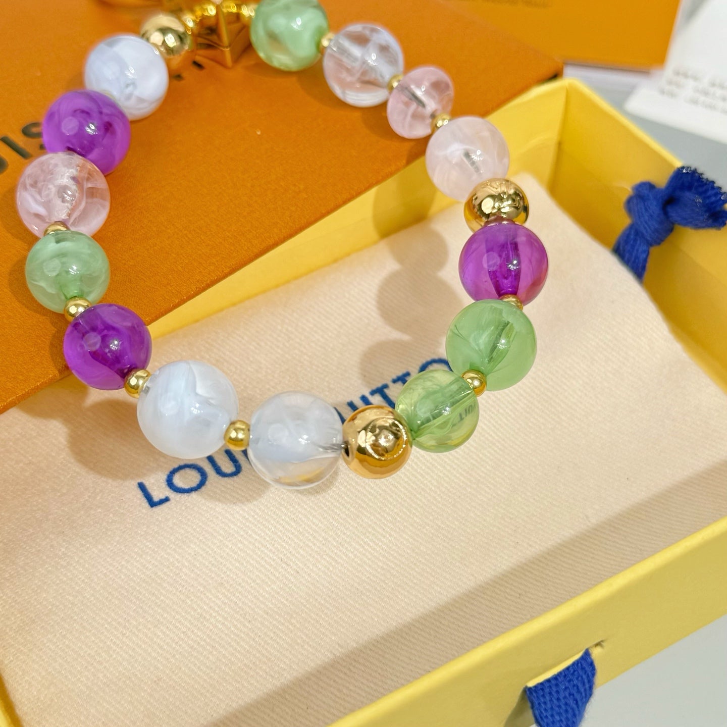 Beaded bracelet with purple, green, and white beads and gold-tone medallion charm