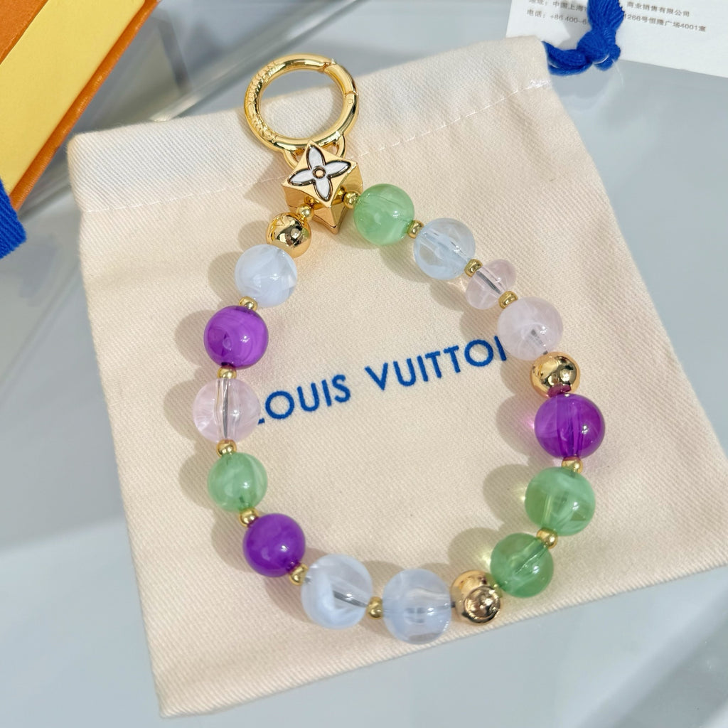 Beaded charm bracelet with gold flower charm, multicolor beads, and blue tassel cord