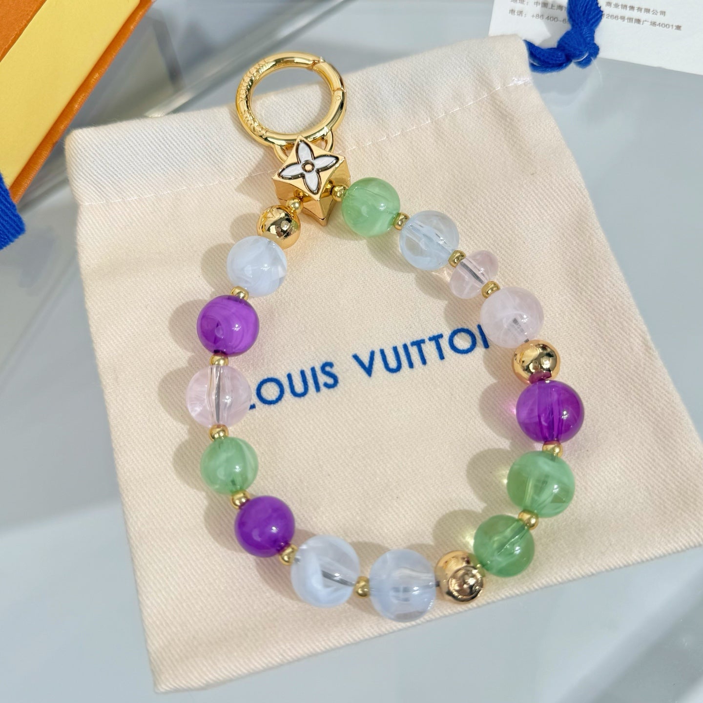 Beaded bracelet with pastel purple, green, and white beads and gold-tone charm ring