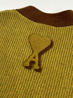 Yellow knit sweater with brown ribbed collar and embroidered logo on chest