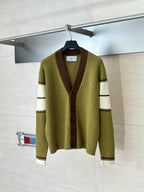 Green knit cardigan with V-neck, brown button placket, and cream striped cuffs