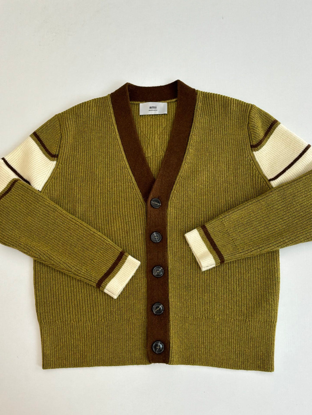 Green knit cardigan close-up with brown V-neck and contrast striped cuffs
