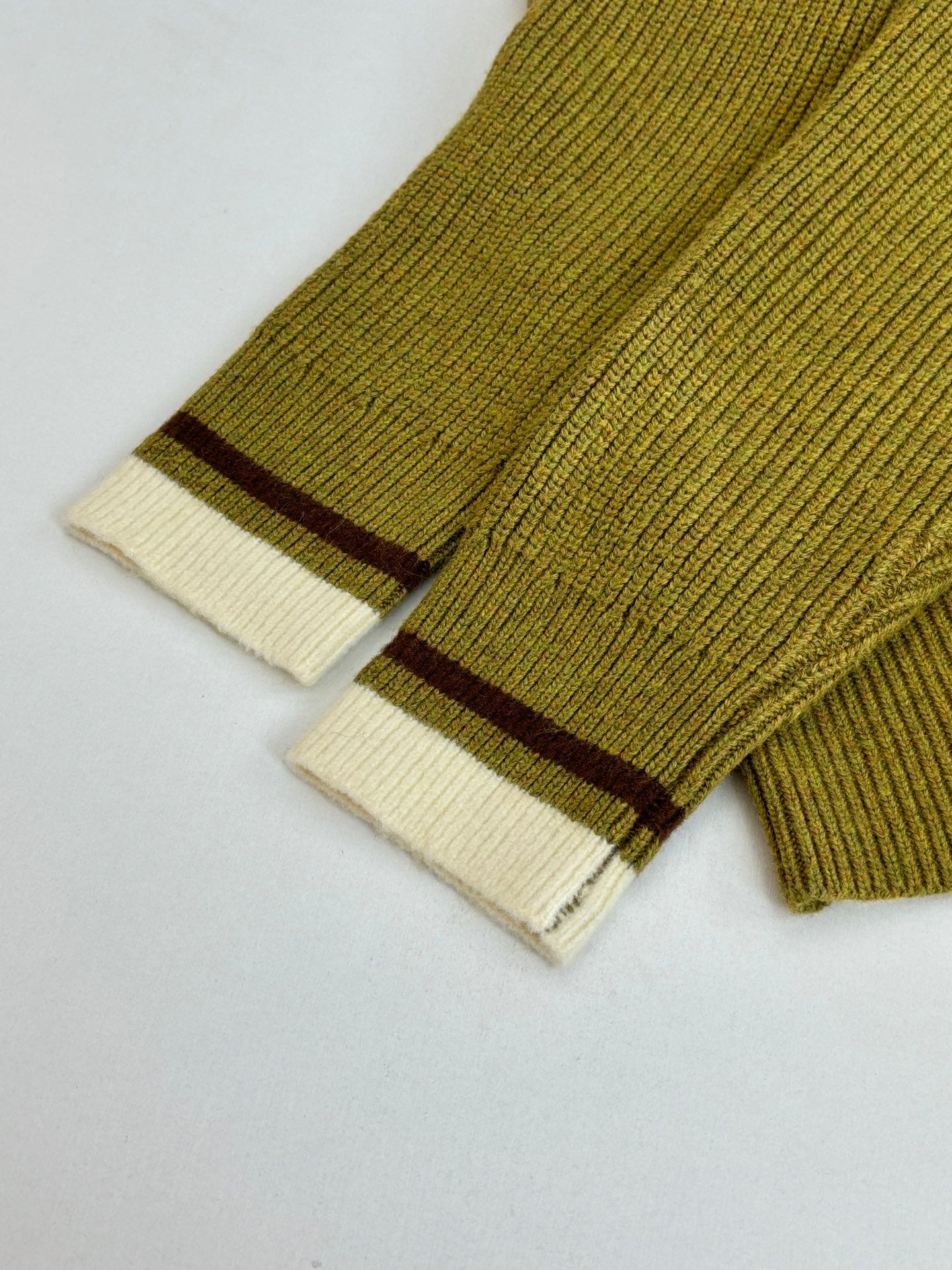 Green knit cardigan cuff with cream ribbing and dark stripe