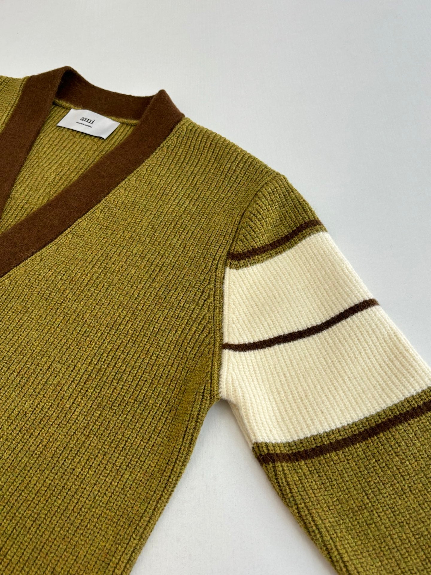 Green knit cardigan sleeve with cream and brown stripe band accents
