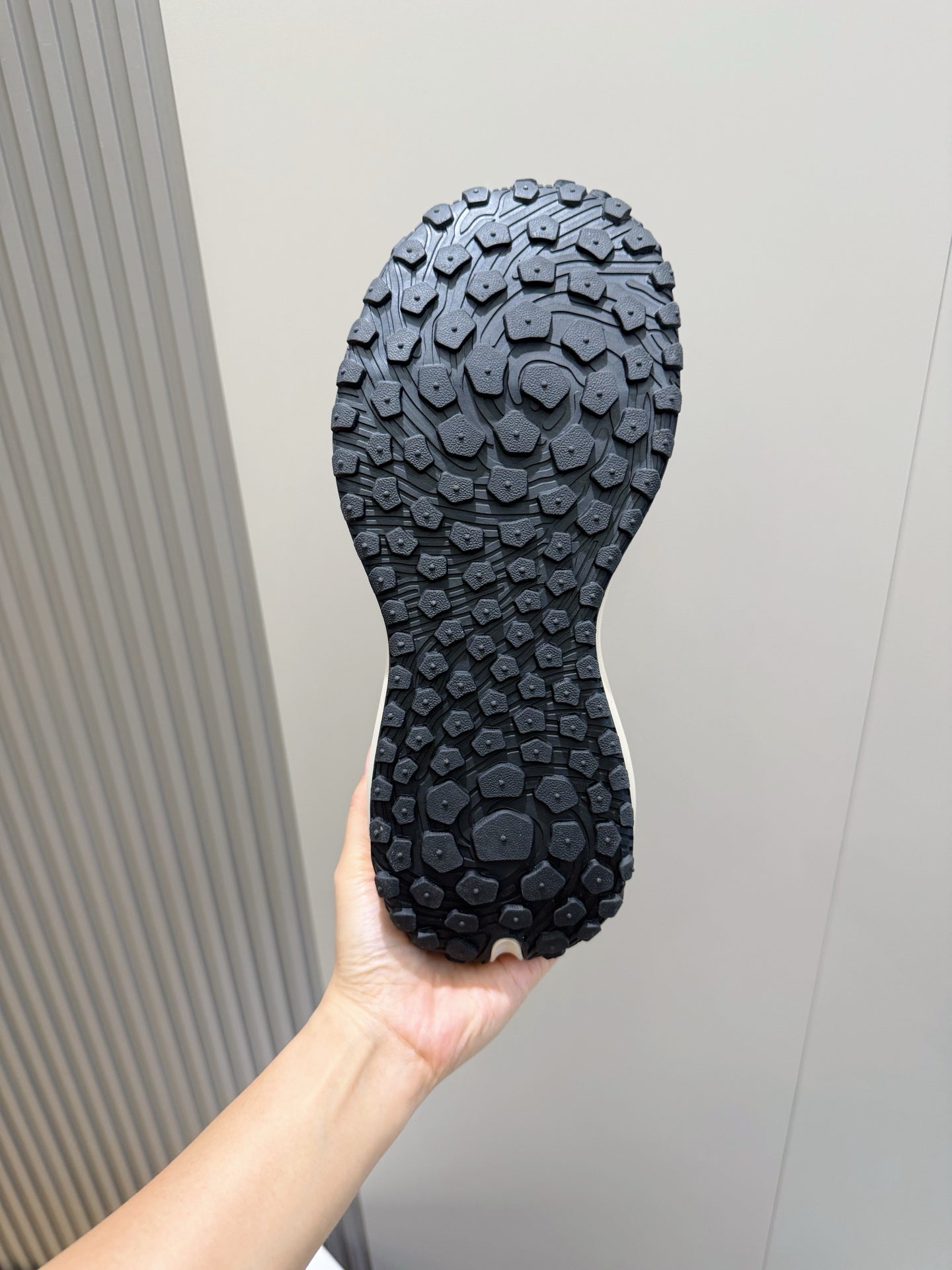 Moncler luxury shoes outsole with dark tread pattern, held in hand