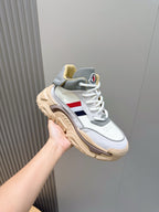 White sneakers with gray upper panels, tan sole, and blue red side stripe