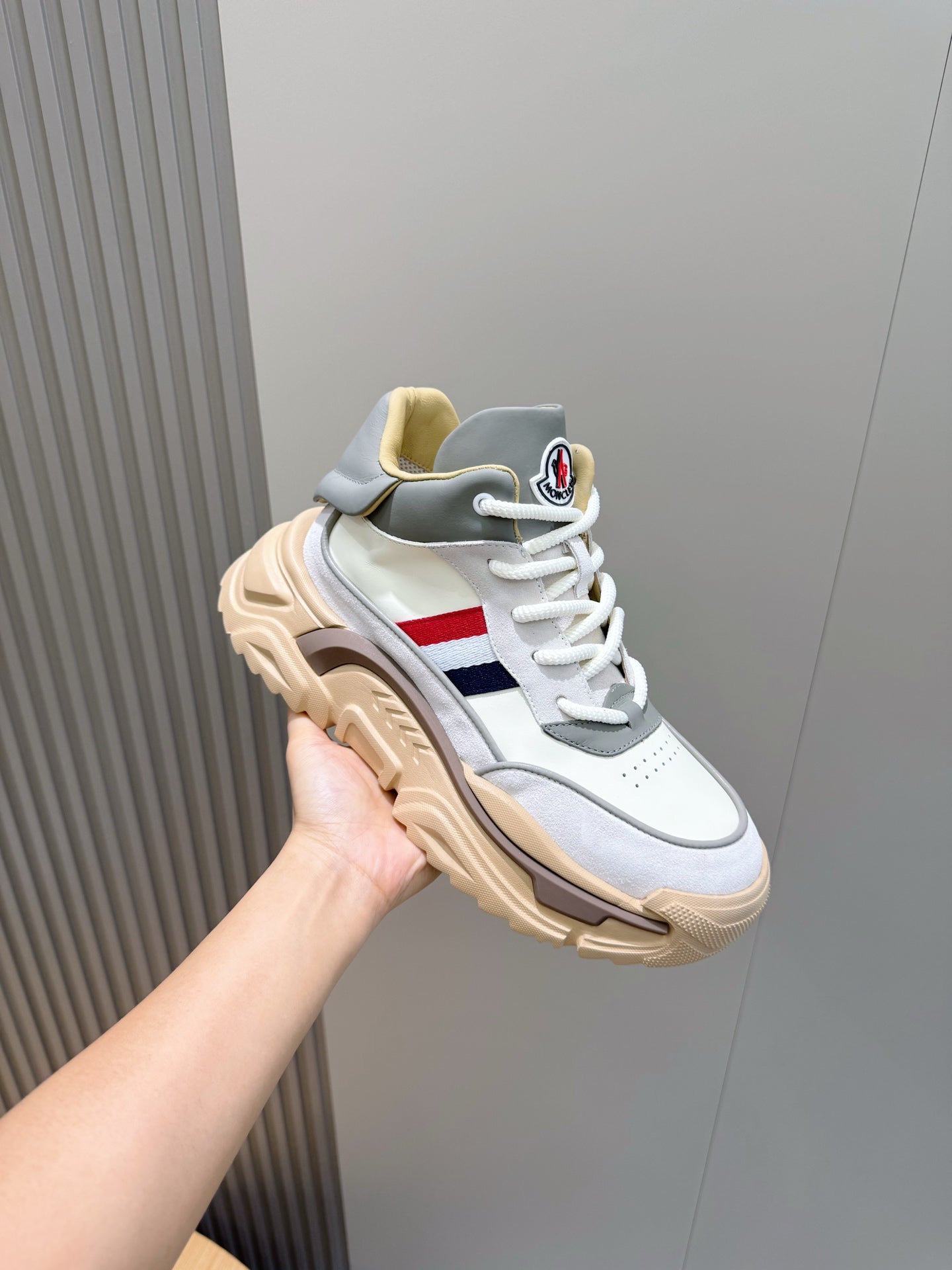 White sneakers with gray upper panels, tan sole, and blue red side stripe