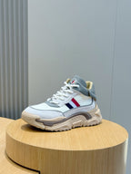 Light blue sneakers with tan sole, lace-up closure, and multicolor side stripe