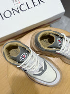 White Moncler sneakers with tan lining and laces, close-up of logo tongues