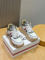 White Moncler sneakers with tan sole, lace-up front, and blue red side stripe