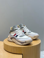 White and light blue sneakers with tan sole, laces, and red blue stripe