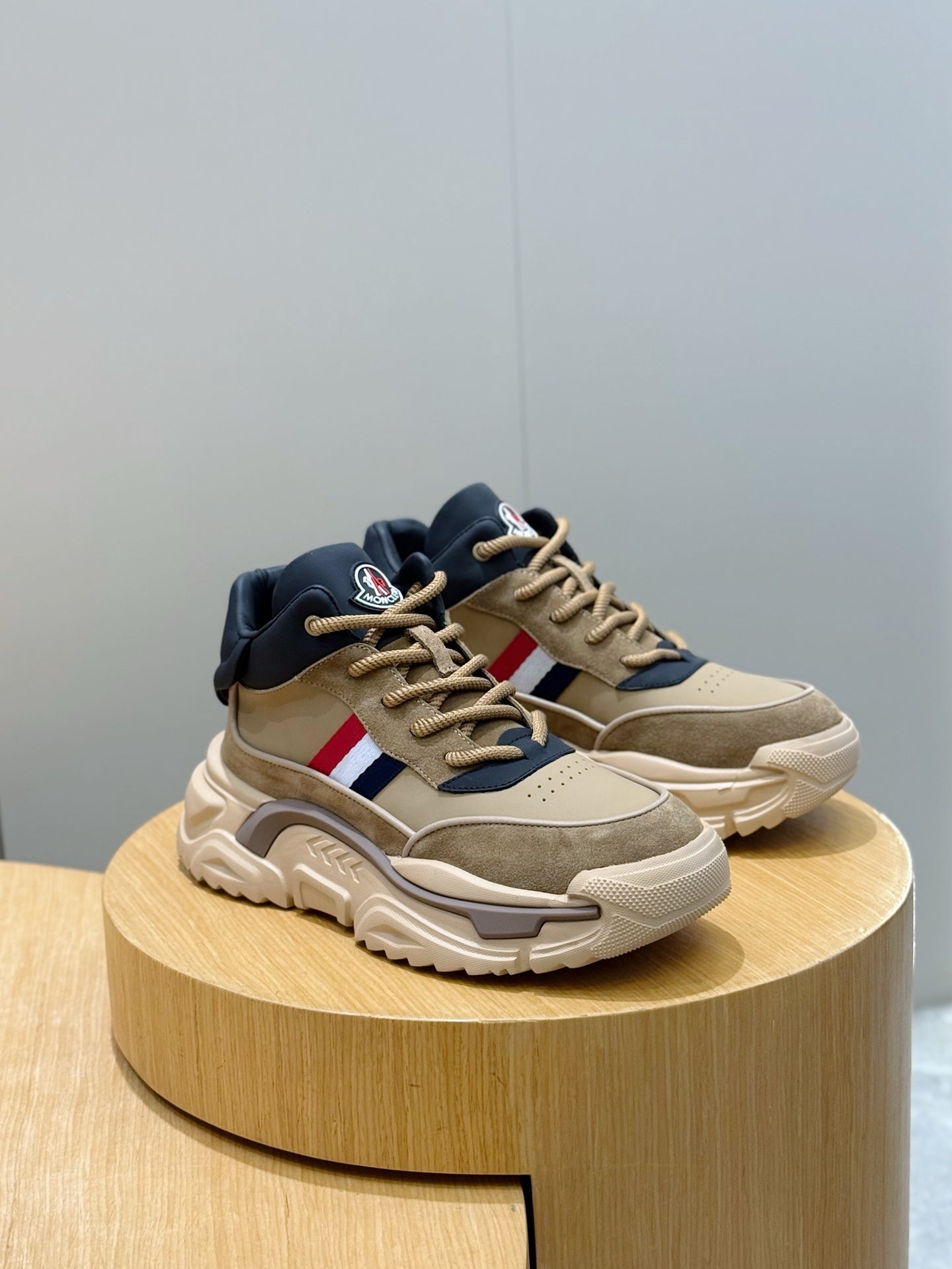 Moncler sneakers on round stand, beige and navy colorblock with red-white stripe