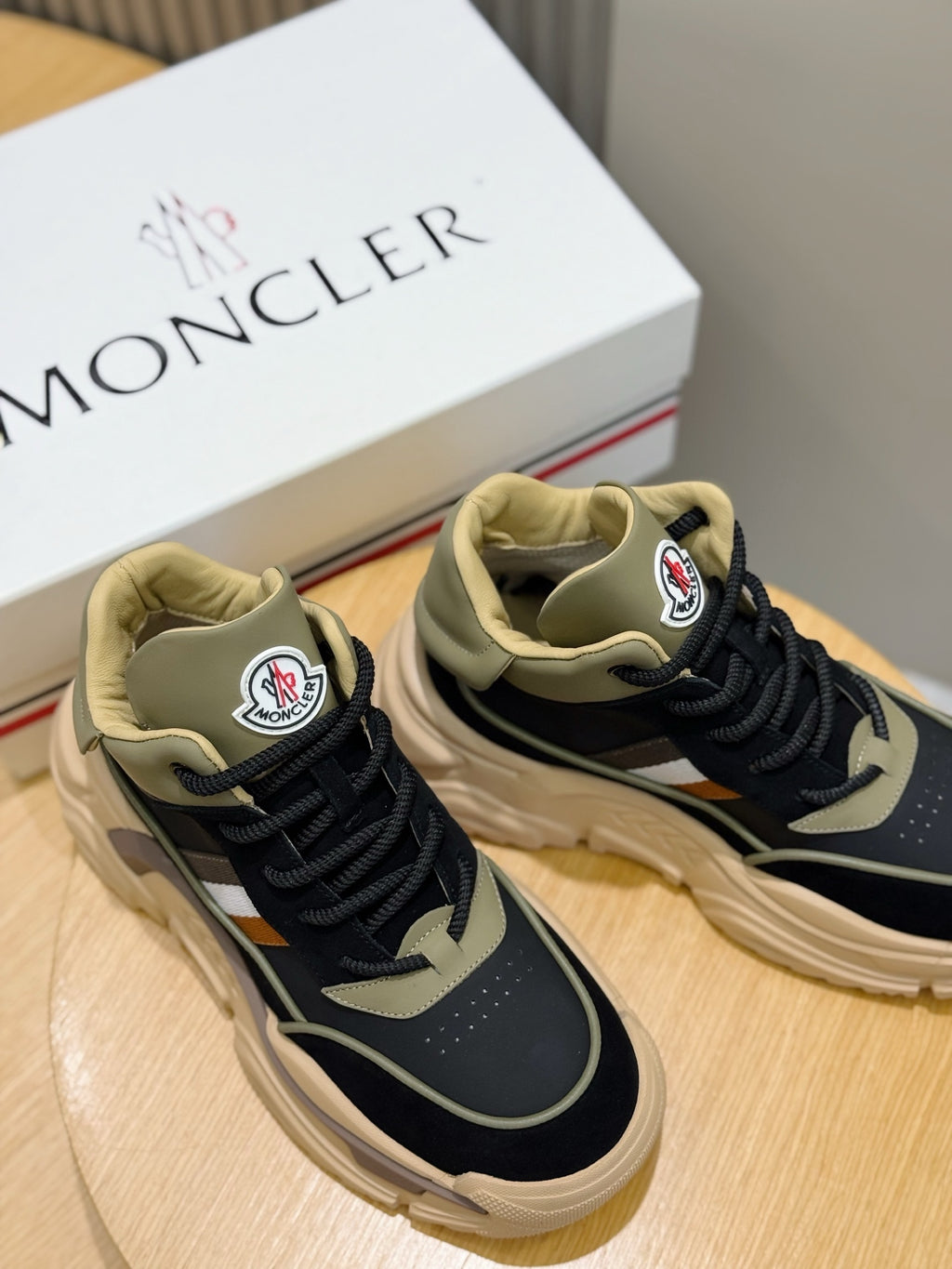 Moncler sneakers on wooden stand, navy uppers with black laces and beige trim