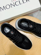 Black sneakers pair with Moncler branding on tongue and heel, white rubber sole