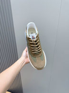 Moncler low-top sneaker held by hand, olive and tan suede with white sole