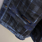 Louis Vuitton logo tag on blue patterned fabric, stitched near seam