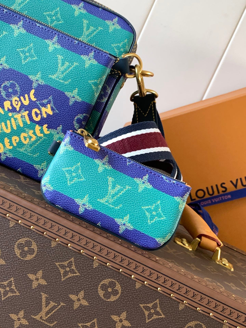 Louis Vuitton men’s crossbody bag close-up with striped strap and gold chain