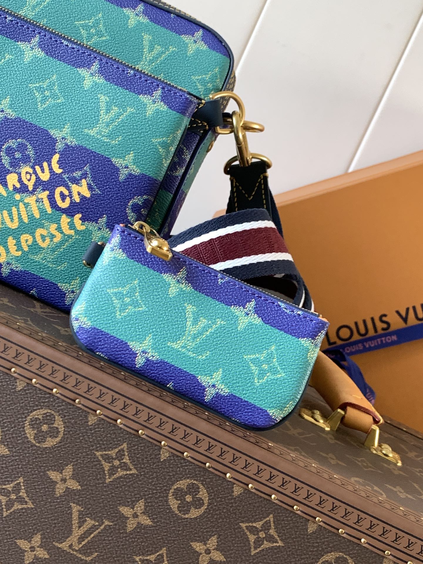 Louis Vuitton men’s crossbody bag close-up with striped strap and gold chain