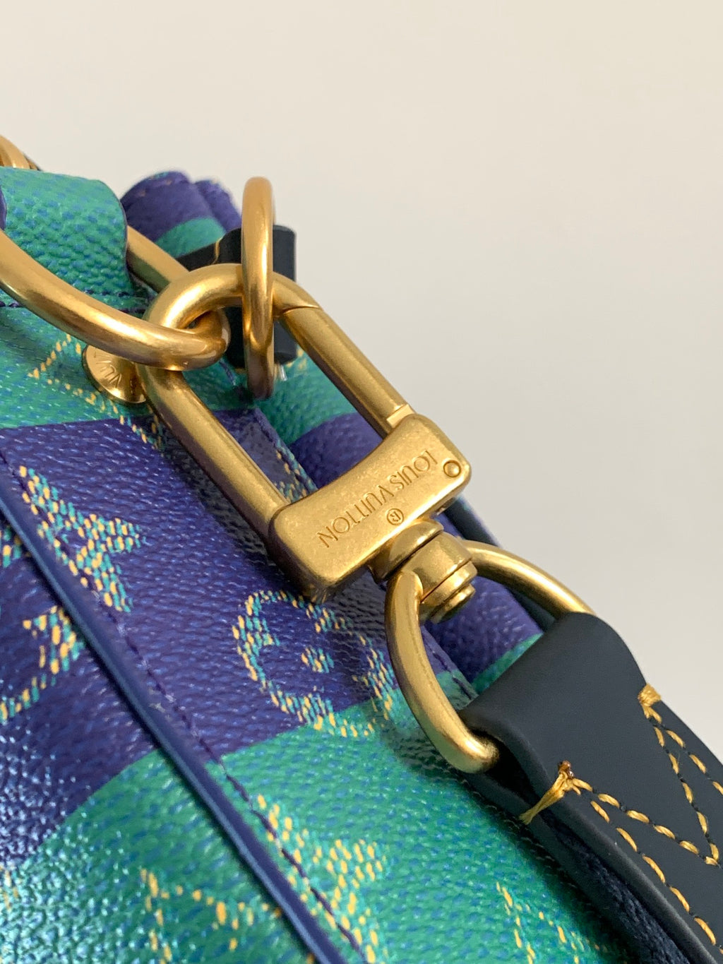 Louis Vuitton men’s crossbody bag clasp close-up in gold with engraved metal