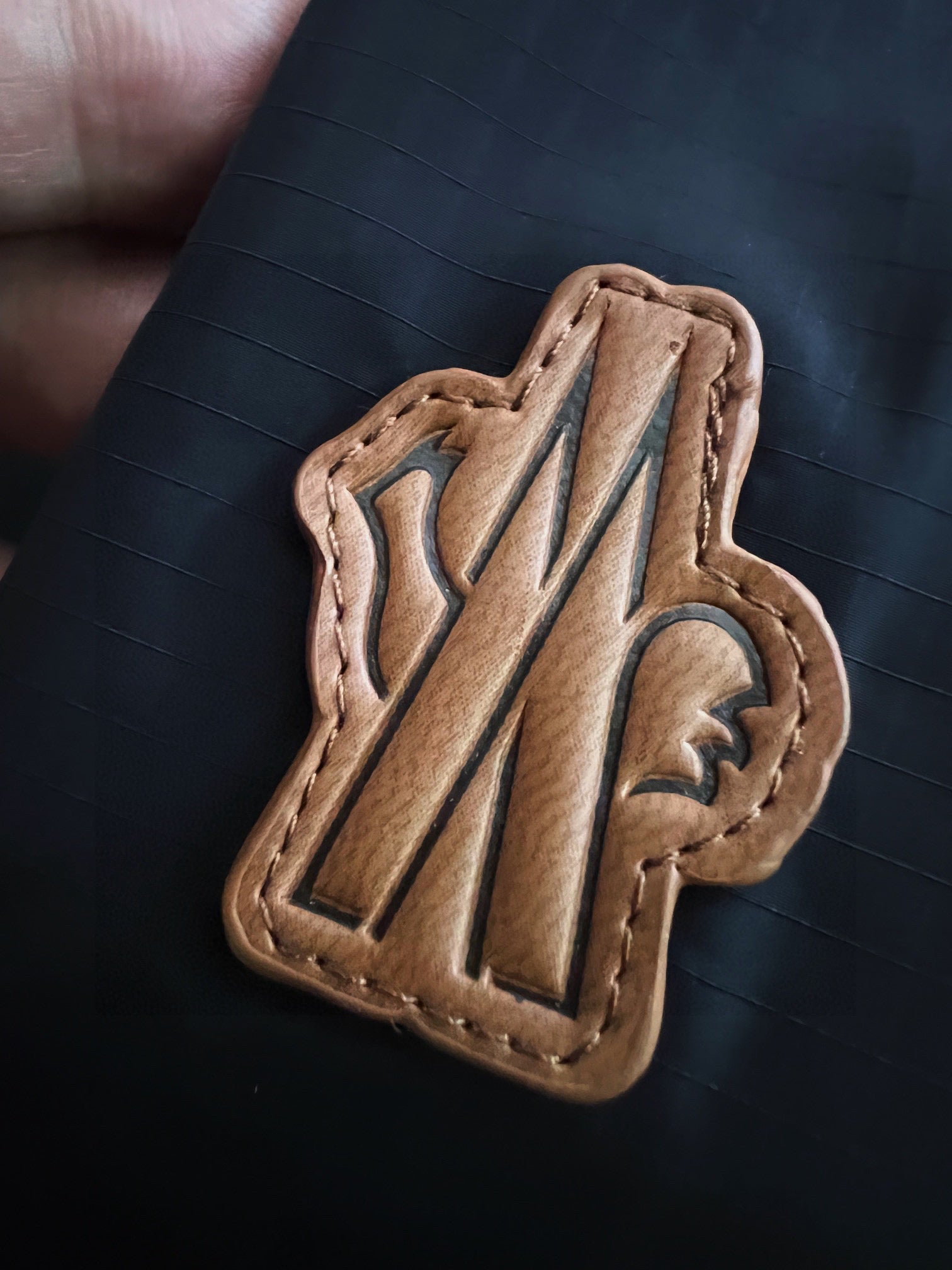 Leather jacket logo patch with stylized M letter on black fabric