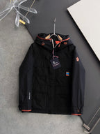 Long black winter jacket with zip front, orange trim, hood and logo patches