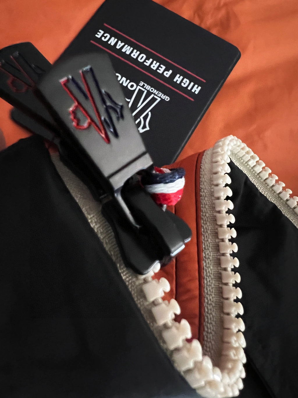 Zipper and branded pull on orange-and-black jacket lining, high-performance tag