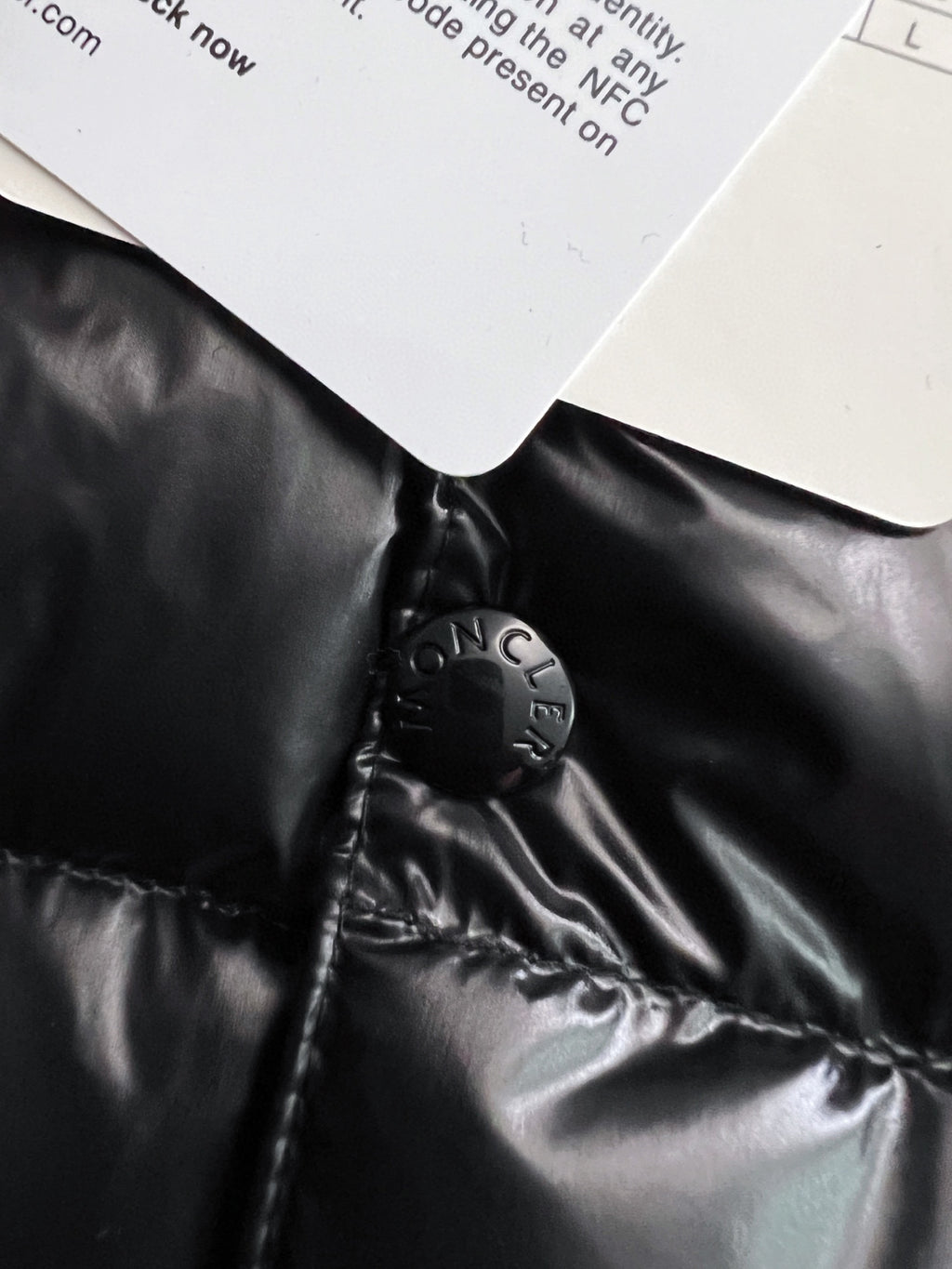 Black puffer jacket collar area with Moncler-engraved snap hardware