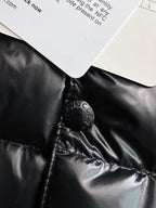 Black puffer jacket collar area with Moncler-engraved snap hardware