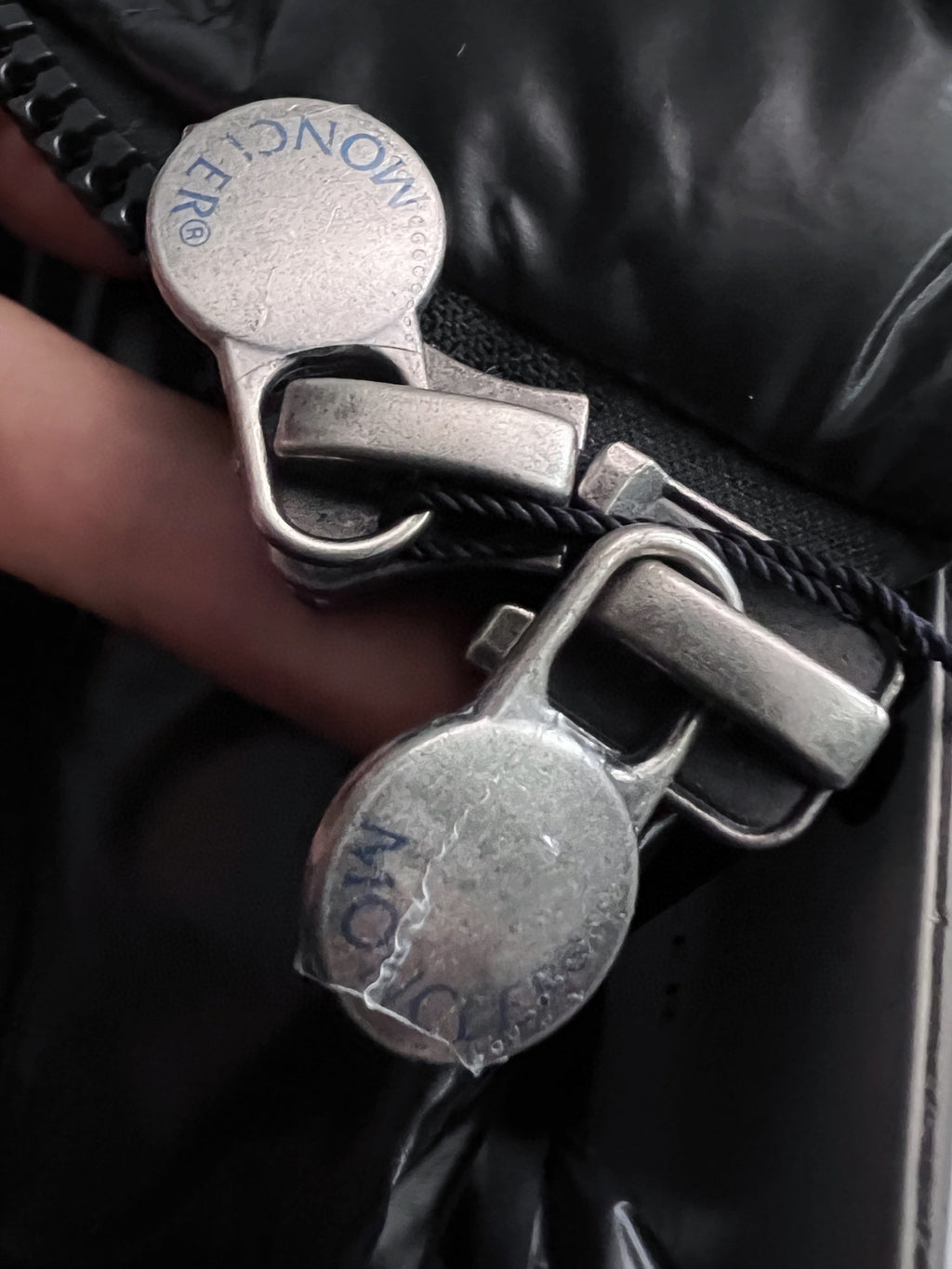 Black puffer jacket zipper pull and snap hardware with embossed logo