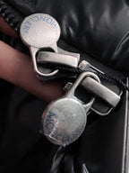 Black puffer jacket zipper pull and snap hardware with embossed logo