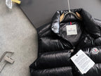 Long black puffer jacket with hood and front snap placket, brand tag visible
