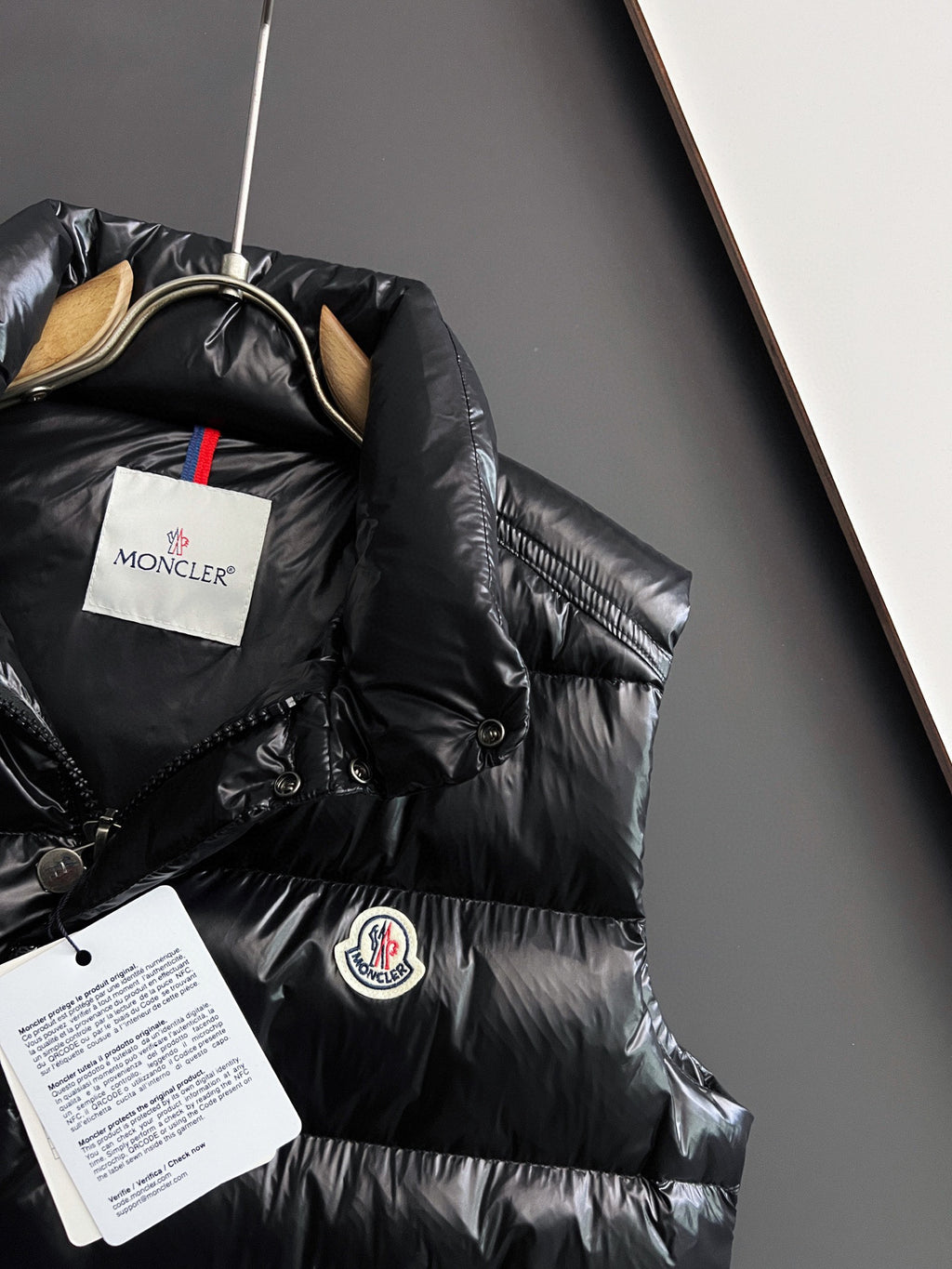 Black long puffer jacket with hood and circular logo patch on the chest