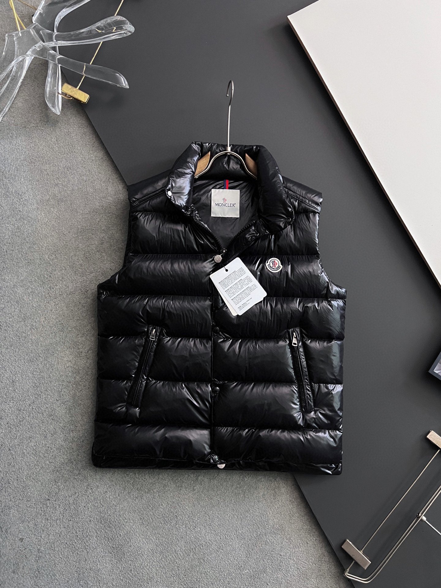 Black long puffer jacket with hood, snap buttons, and hanging tags